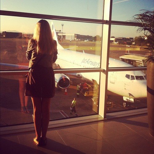 How to save money on buying air tickets, a girl looks out the window at the airport