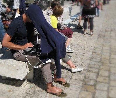 man in hoodie, laptop on lap, summer